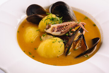 Creamy seafood soup with mussels, potatoes and small octopus