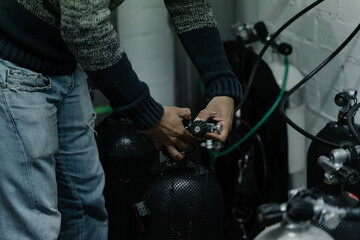 Detail of a man's hands checking the gas in an oxygen cylinder inside a ship.