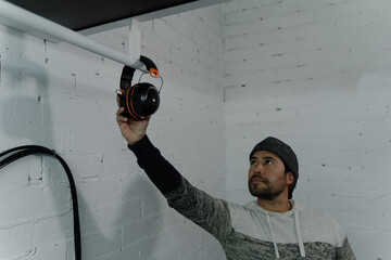 Man in a cap hanging wireless helmets on a pipe