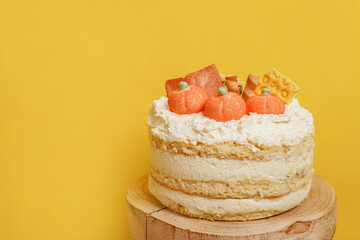 Autumn cake with pumpkins staying on the wood on yellow background, thanksgiving cooking