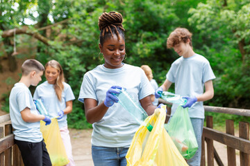 A multiethnic group of people, cleaning together in a public park, are protecting the environment. The concept of recycling and cleaning