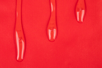 transparent varnish, clear oil drops on red paper copy space background