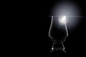 Shining whisky glass, silhouette of a whiskey glass with black background and interesting light effect. Transparent empty glass of whiskey. Copy space for your design. Web banner. 