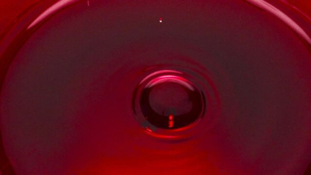 Circle shaped wine drops falling into glass closeup. 