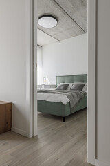 Fototapeta na wymiar Modern minimalistic bedroom interior design in grey shades with light green bed, eucalyptus in glass vase, concrete ceiling. Scandinavian style. Aesthetic simple interior design concept.