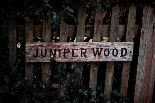 Fence Made Of A Juniper Wood With A Wooden Sign On It