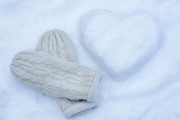 snowy heart with knitted mittens on a background of white snow, I love winter, valentines day