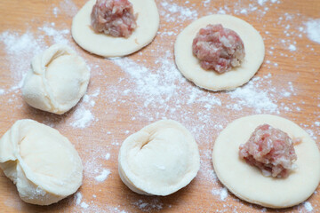 Dumplings with meat. Vareniki Homemade. Flour, dough on a wodden background. Home cooking dumplings, dough and minced meat