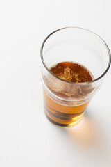 Overhead image of half full pint glass of lager beer, with copy space on white background