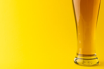 Horizontal image of pint glass of lager beer on yellow background, with copy space