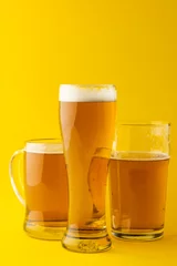 Gordijnen Image of three different pint glasses of lager beer, with copy space on yellow background © vectorfusionart