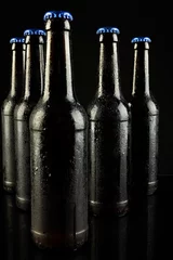 Gordijnen Image of five beer bottles with blue crown caps, with copy space on black background © vectorfusionart