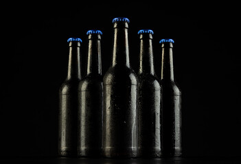 Image of five beer bottles with blue crown caps, with copy space on black background - obrazy, fototapety, plakaty