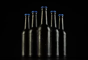 Fotobehang Image of five beer bottles with blue crown caps, with copy space on black background © vectorfusionart