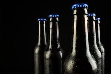 Image of five beer bottles with blue crown caps, with copy space on black background - obrazy, fototapety, plakaty