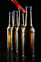 Gordijnen Image of red bottle opener and four beer bottles with blue crown caps, with copy space on black © vectorfusionart