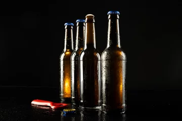 Foto op Canvas Image of red bottle opener and four beer bottles one open, with copy space on black © vectorfusionart