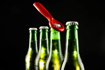 Foto op Canvas Image of red bottle opener and four green beer bottles with crown caps, with copy space on black © vectorfusionart