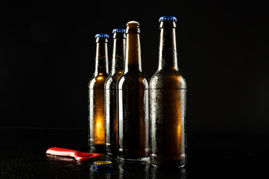 Image of red bottle opener and four beer bottles one open, with copy space on black