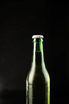 Image of green glass beer bottle with white crown cap, with copy space on black background