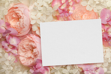 Floral Composition and blank paper card with copy space for invitation text. Greeting card close up with pink roses and hyrangea flowers. Romantic Wedding or Birthday Mock-up Scene. 