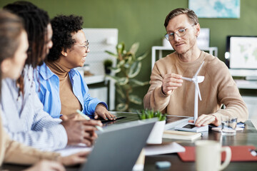 Young businessman showing the work of windmill to his colleagues during meeting