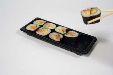 chopsticks grabing a piece of sushi from a sushi set