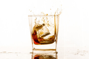 Portrait of whiskey splash glass with ice isolated on white background studio.