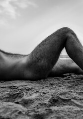 Monochrome of shirtless adult man lying on beach