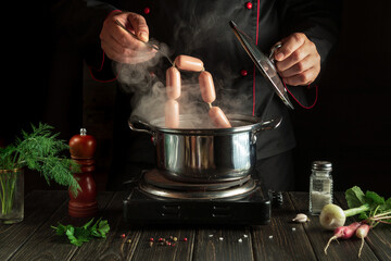 The chef puts Vienna sausage in a saucepan. Working environment in the kitchen of a restaurant or cafe. Preparing breakfast or dinner