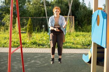 Girl on swing in summer. Teen swinging. Student on playground.