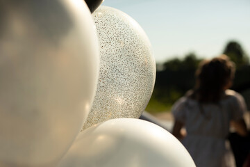 White balloons in sunlight. Details of holiday. Balls in rays of light.
