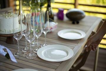 Plates and glasses on table. Table on veranda. Details of holiday. Preparing for dinner.