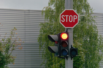 Stop street sign and red traffic light attached to a metal pole 