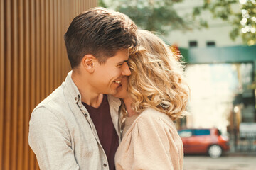 Fototapeta premium Content couple of a smiling man embracing lovely blonde woman in the street. Close up outdoor portrait.