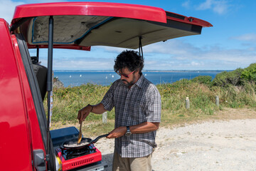 Young middle-aged adventure sucker cooking in his van life 