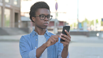 Young African Man Browsing Internet on Smartphone Outdoor
