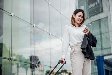 Young Asian businesswoman talking on phone and sitting in airport before business trip. Beautiful woman passenger has mobile call and discusses something with smile, holds coffee in hand