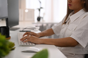 Cropped view of female programmer hands typing on keyboard, writing program code on computer