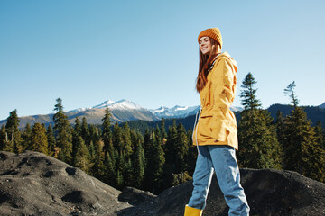 Naklejka premium Woman smile with teeth happiness and laughter hiker in yellow raincoat put her hands up and jumping trip in the fall and hiking in the mountains in the sunset freedom