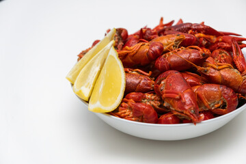 Fresh red boiled crayfish food on a plate on a white background. Healthy seafood snack with lemon.