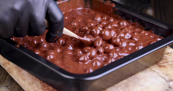 adding roasted hazelnuts to melted liquid chocolate