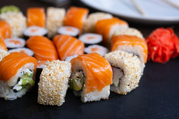 Delicious fresh sushi roll set on a black board. Sushi roll with rice, cream chees, red fish, salmon. Sushi menu. Japanese kitchen, restaurant. Seafood, asian food