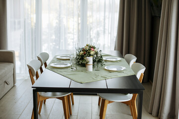 in a bright room, with daylight, a festive table is decorated, with plates and glasses