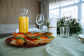 in a bright room, with daylight, a decorated festive table, with plates of food and glasses of orange juice