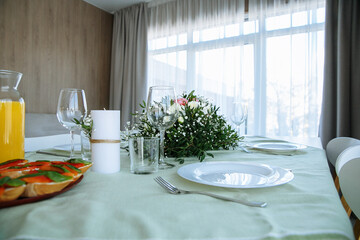 in a bright room, with daylight, a decorated festive table, with plates of food and glasses of orange juice