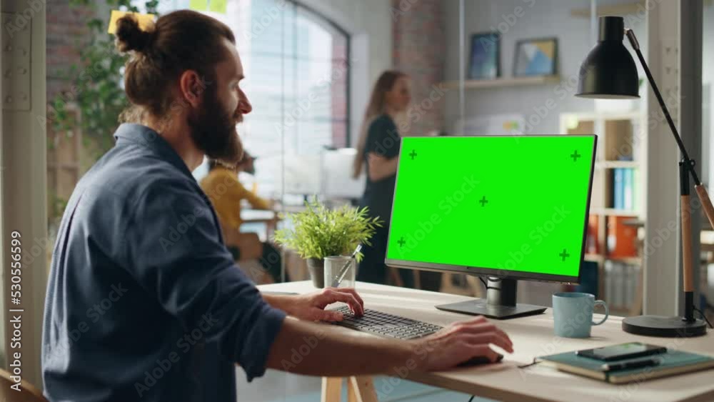 Fototapete Creative Project Manager Working on Desktop Computer with Green Screen Mock Up Display. Bohemian Style Inspired Handsome Marketing Specialist Planning a Project, Browsing Internet and Writing Emails.
