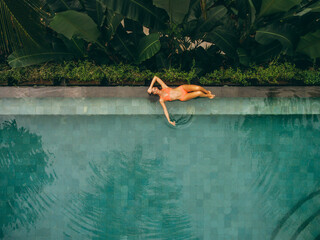 Beautiful woman lying at the poolside - obrazy, fototapety, plakaty