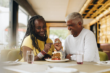 Happy mature couple eating a cake together in a cafe