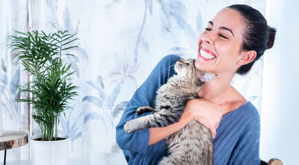 Super happy and smiling woman hugs her cat.